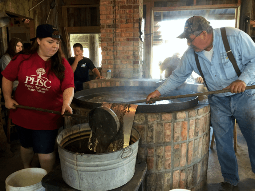 Charlie Kirksey and the newest protege of the Cane Cookers work to remove impurities as the syrup heats up.