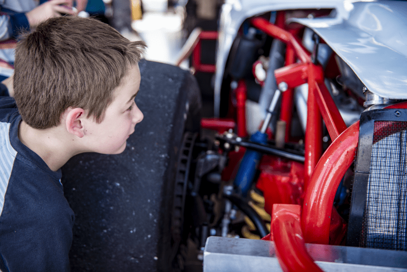 Kid looking at suspension on vehicle