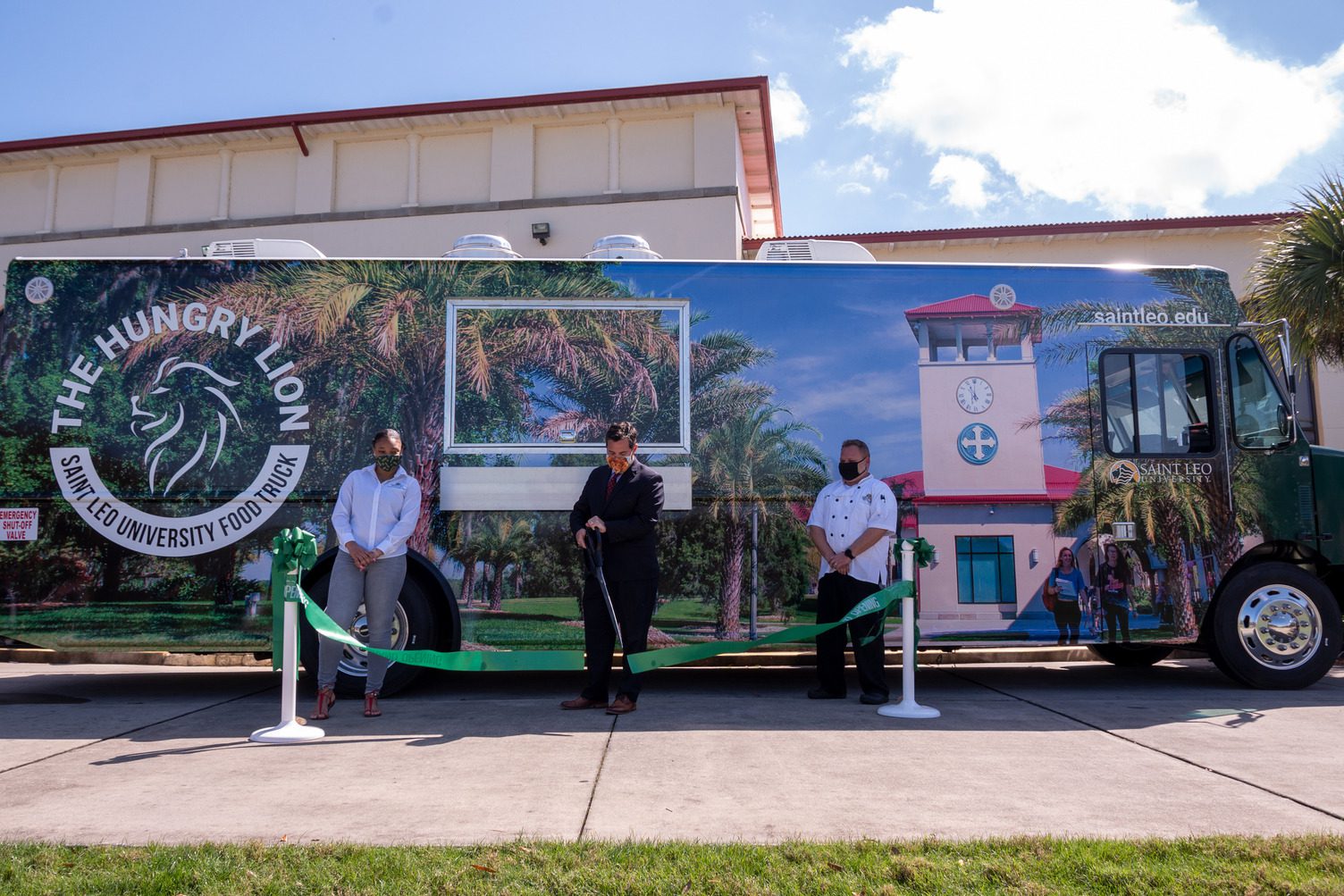 Saint Leo University President Jeffrey Senese (center), alongside Student Government Union President Ashley Butler (left) and Director of Dining Services Justin Bush (right), cut the ribbon signifying the opening of The Hungry Lion food truck.